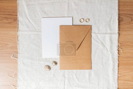Téléchargez les photos : Enveloppe artisanale avec alliances sur table en bois - en image libre de droit