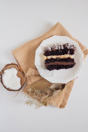 Photo for Plate of chocolate cake slice with coconut on beige cloth. Party comfort food concept. - Royalty Free Image