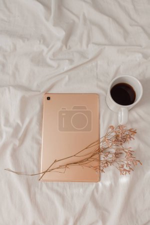 Foto de Otoño, composición de otoño. Una taza de café en la cama de lino beige y una tableta de oro rosa. Estilo de vida, concepto de temporada de moda. - Imagen libre de derechos