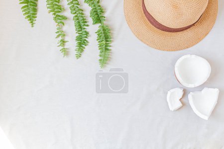 Téléchargez les photos : Chapeau de paille, noix de coco et feuilles vertes. Accessoire féminin pour l'été. Concept de mode. - en image libre de droit