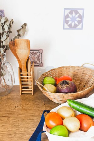 Foto de Grupo de verduras frescas en cesta de paja y bolsa de compras sobre fondo de madera. - Imagen libre de derechos
