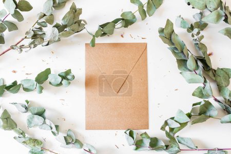 Photo for Round frame made of eucalyptus leaves and branches on white background with craft envelope. - Royalty Free Image