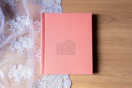 Foto de Álbum de fotos rosa sobre tela blanca y mesa de madera - Imagen libre de derechos