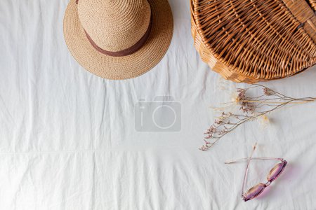 Foto de Vista superior de la cesta de picnic con flores secas, gafas de sol y sombrero de paja - Imagen libre de derechos