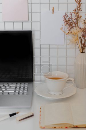 Foto de Concepto de negocio. Escritorio minimalista de oficina en casa con computadora portátil, taza de té y suministros fijos - Imagen libre de derechos