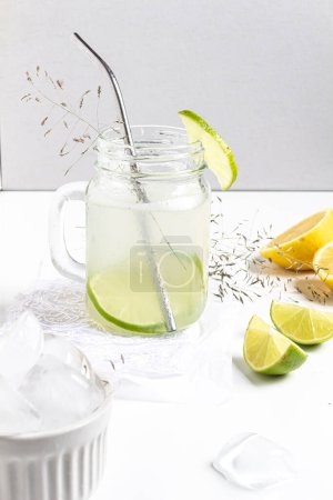 Foto de Concepto de bebida fría de verano. Vidrio con limonada verde y cítricos en rodajas sobre fondo blanco. - Imagen libre de derechos