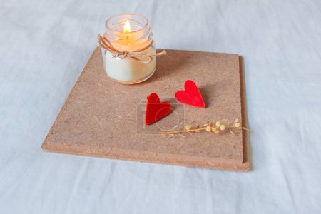 Téléchargez les photos : Bougie allumée avec un cœur rouge sur une planche de liège sur un fond gris. concept de Saint-Valentin - en image libre de droit