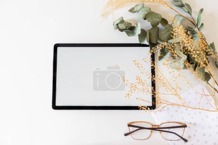 Foto de Vista superior de la tableta digital decorada con flores secas sobre fondo blanco - Imagen libre de derechos