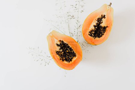 Foto de Concepto de verano. Composición minimalista de alimentos frescos. Vista superior de las mitades de papaya naranja tropical sobre fondo blanco. - Imagen libre de derechos