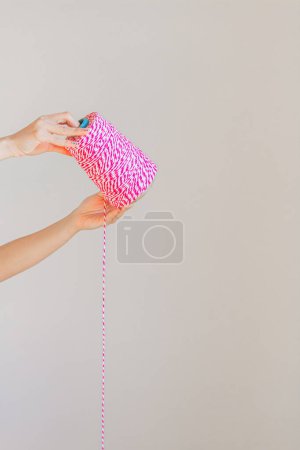 Foto de Manos femeninas sosteniendo rollo de cuerda rosa. Concepto artesanal. - Imagen libre de derechos