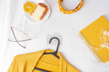 Téléchargez les photos : Home office desk frame with orange piece of cake, cardigan, glasses and planner on white background. - en image libre de droit