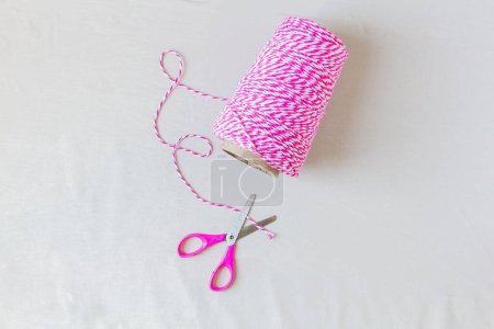 Foto de Cuerda de rayas rosadas y tijeras sobre fondo blanco. Concepto artesanal. - Imagen libre de derechos