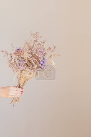 Foto de Mano de mujer joven sosteniendo un ramo de flores secas - Imagen libre de derechos
