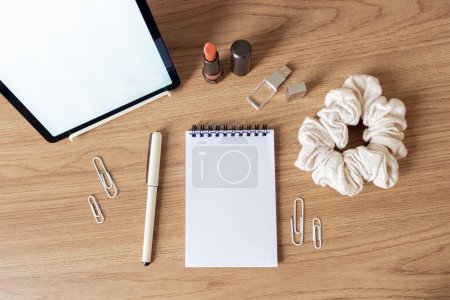 Photo for Digital tablet with empty screen, lipstick, scrunchie and office supplies on wooden table - Royalty Free Image