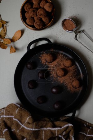 Photo for Top view of homemade chocolate truffles covered with cocoa powder in black pan. Gray background. Delicious dessert concept. - Royalty Free Image