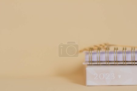 Téléchargez les photos : 2023 planificateur sur fond beige. Espace de copie. Composition minimaliste. - en image libre de droit