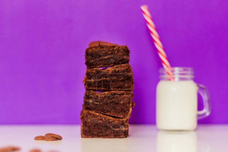 Foto de Brownie y vaso de leche sobre fondo morado. Composición de estilo de comida moderna - Imagen libre de derechos