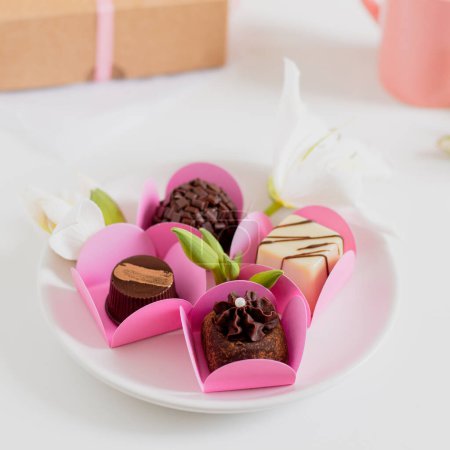 Téléchargez les photos : Bonbons au chocolat sur fond blanc. Composition printemps féminine. Stylisme alimentaire. - en image libre de droit