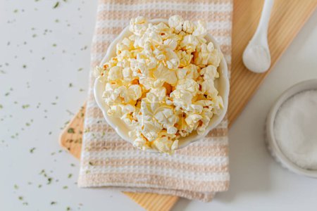 Photo for Top view of popcorn plate on kitchen towel and wooden board - Royalty Free Image