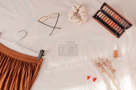 Photo for Female styled accessories: glasses, scrunchie, wildflowers, cosmetics and skirt on white background. - Royalty Free Image