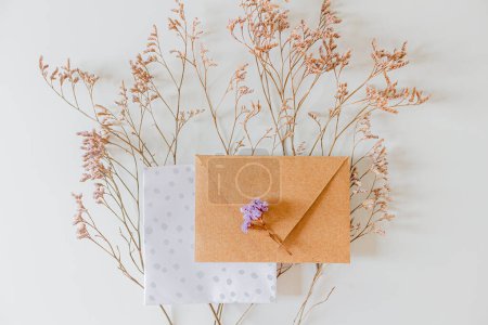 Photo for Wedding invitation envelope, lilac flowers on white background. Flat lay, top view. - Royalty Free Image