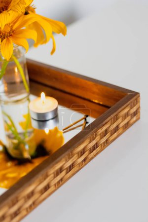 Téléchargez les photos : Bouquet de tournesols avec bougie allumée sur plateau miroir. Composition minimaliste esthétique. - en image libre de droit
