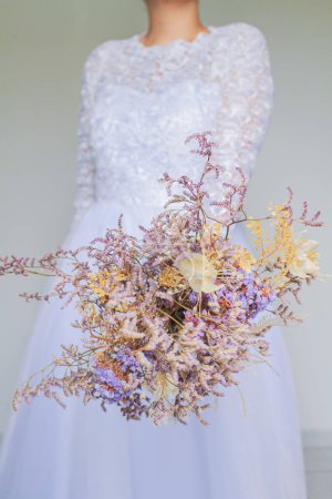 Foto de Joven y bonita novia sosteniendo un ramo de flores secas - Imagen libre de derechos