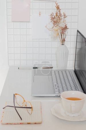 Foto de Concepto de negocio. Escritorio minimalista de oficina en casa con computadora portátil, taza de té y suministros fijos - Imagen libre de derechos