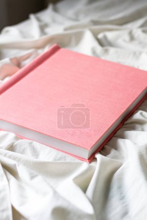 Téléchargez les photos : Album photo rose sur drap de lit blanc - en image libre de droit