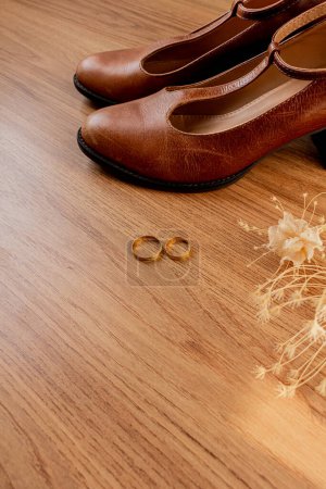 Téléchargez les photos : Chaussures de mariée vintage sur une table en bois, papeterie de mariage et fleurs séchées. Couché à plat, vue de dessus. Concept de préparation de mariage. - en image libre de droit
