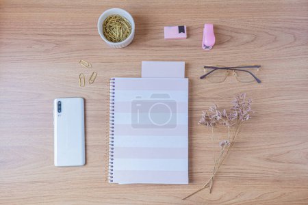 Foto de Espacio de trabajo con cuaderno, smartphone y artículos de papelería sobre fondo de madera. Piso tendido, vista superior - Imagen libre de derechos