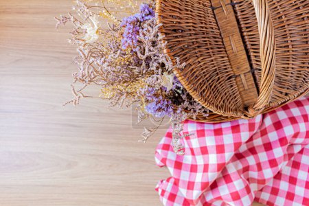 Photo for Top view of picnic basket with a bunch of dried flowers inside - Royalty Free Image