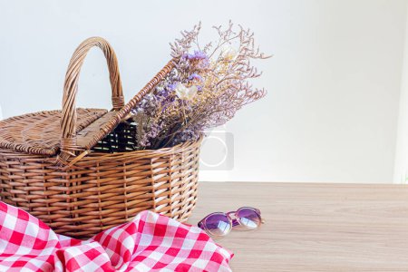 Photo for Picnic basket with a bunch of dried flowers inside - Royalty Free Image