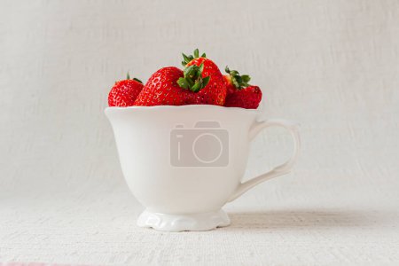 Téléchargez les photos : Pleine tasse de fraises fraîches sur fond blanc - en image libre de droit