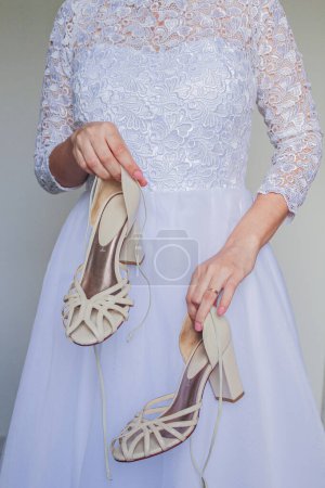 Téléchargez les photos : Jeune et jolie mariée tenant des chaussures - en image libre de droit