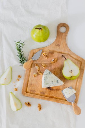 Téléchargez les photos : Composition avec fromage bleu, poires vertes et cerneaux de noix sur la planche à découper - en image libre de droit