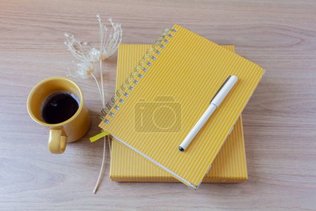 Foto de Espacio de trabajo del escritorio de la oficina del hogar femenino con una taza de café, planificadores, pluma, flores silvestres en la mesa de madera. - Imagen libre de derechos