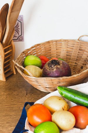 Foto de Grupo de verduras frescas en cesta de paja y bolsa de compras sobre fondo de madera. - Imagen libre de derechos