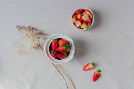 Photo for Strawberries on a sugar pot and a bowl on a white background. - Royalty Free Image