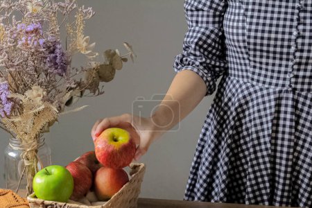 Foto de Concepto de otoño. Recortado tiro de mujer en vestido a cuadros tomando manzana roja de la cesta - Imagen libre de derechos