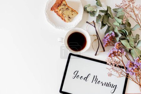 Téléchargez les photos : Phrase "bonjour" sur un comprimé, cadre floral et composition du petit déjeuner sur fond blanc. Concept matin lent. - en image libre de droit