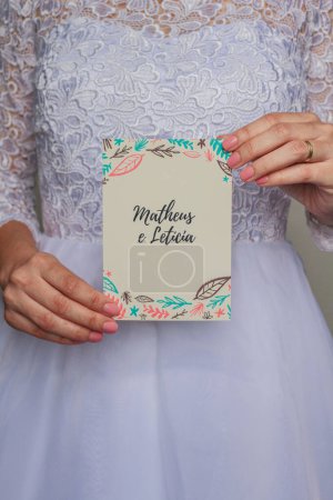 Foto de Mujer joven vistiendo un vestido de novia y sosteniendo un sobre artesanal, su invitación de boda - Imagen libre de derechos