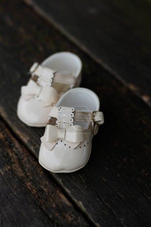 Photo for Little white baby shoes on wood background - Royalty Free Image