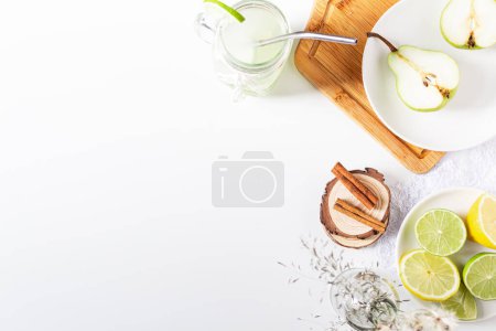 Foto de Concepto de bebida fría de verano. Vidrio con limonada verde sobre fondo blanco con frutas en rodajas - Imagen libre de derechos