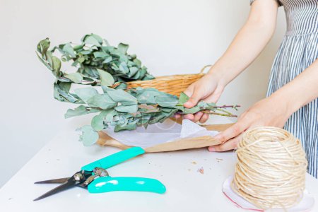 Photo for Florist making an eucalyptus bouquet on white background. Florist minimal concept. - Royalty Free Image
