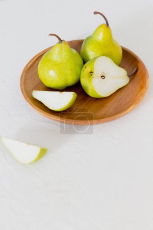 Photo for Juicy pears on a wooden plate on white table - Royalty Free Image