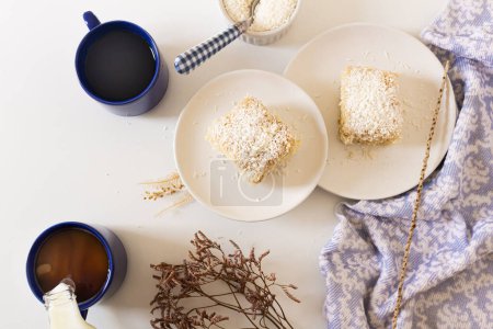 Téléchargez les photos : Vue du dessus de la composition confortable petit déjeuner avec gâteau à la noix de coco dans des assiettes et des tasses de café - en image libre de droit