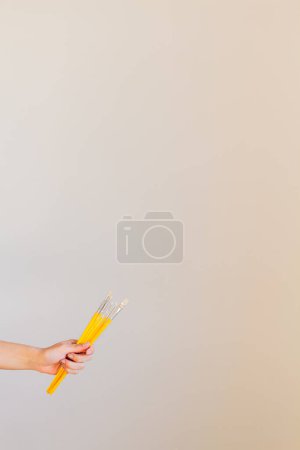 Téléchargez les photos : Main femelle tenant un tas de pinceaux jaunes - en image libre de droit