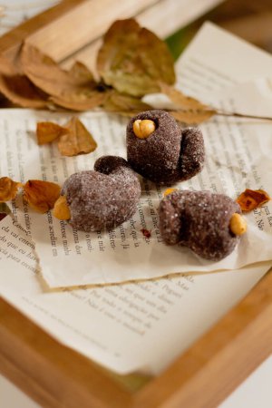 Téléchargez les photos : Bonbons au chocolat décorés de feuilles séchées sur plateau en bois - en image libre de droit