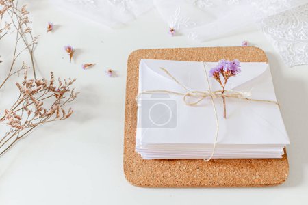 Foto de Composición de invitaciones de boda beige. Sobres blancos, flores secas, encaje textil, cuerda de sisal sobre fondo blanco. - Imagen libre de derechos
